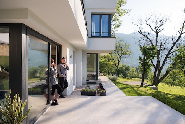 jeune beau beau couple appréciant le café du matin à la porte de leur villa de luxe