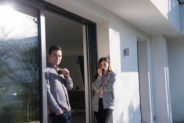 jeune beau beau couple appréciant le café du matin à la porte de leur villa de luxe