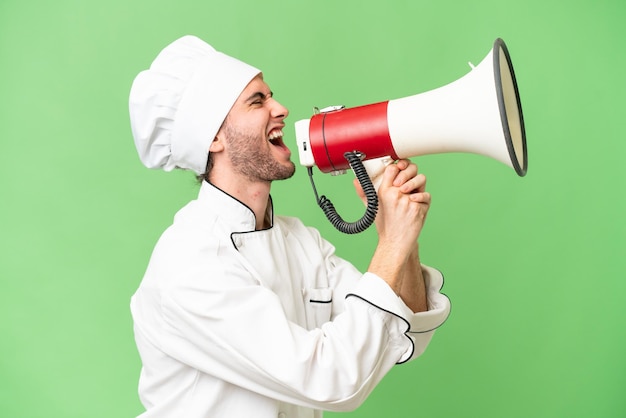 Jeune beau chef homme sur fond isolé criant à travers un mégaphone