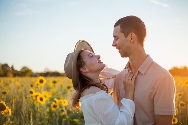 Jeune beau couple amoureux dans un champ de tournesols au coucher du soleil