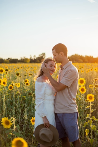 Jeune beau couple amoureux dans un champ de tournesols au coucher du soleil