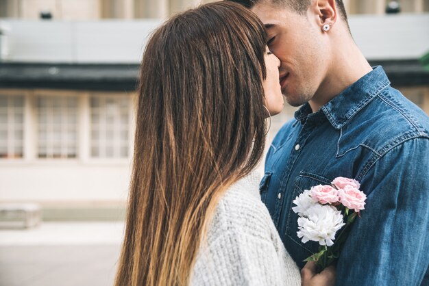 Jeune Beau Couple Amoureux S'embrassant Au Milieu De La Rue De Façon Romantique Avec Des Fleurs