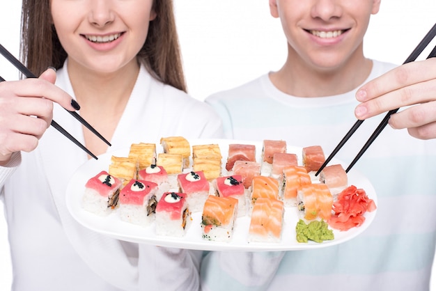 Jeune beau couple avec une assiette de sushi.