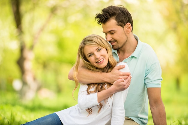 Jeune beau couple assis sur la pelouse du parc de l&#39;été.