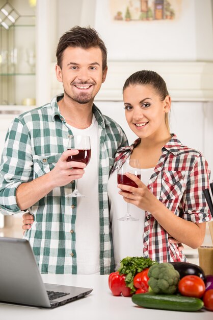 Jeune beau couple boit du vin dans la cuisine.