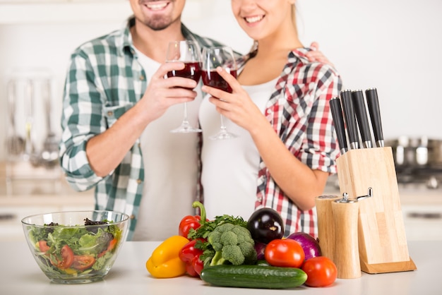 Jeune beau couple boit du vin dans la cuisine.