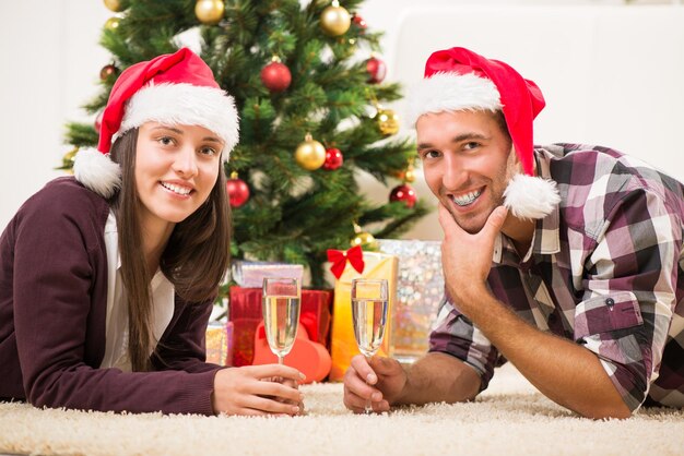Jeune beau couple célébrant Noël ou le nouvel an avec une coupe de champagne.