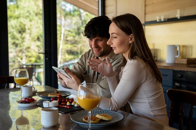 Jeune beau couple dans la salle à manger une famille de deux personnes utilise une tablette en position assise