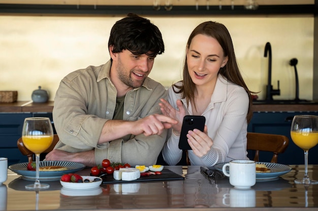 Jeune beau couple dans la salle à manger une famille de deux personnes utilise une tablette en position assise