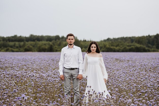 Jeune beau couple debout dans un champ violet en fleurs