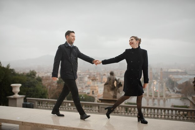 Jeune beau couple espagnol amoureux câlins sous la pluie devant le Musée National d'Art de Catalogne. Tourné dans le contexte de la Plaza Spain à Barcelone.