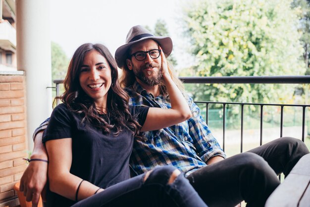 Jeune beau couple heureux à la maison assis terrasse étreignant