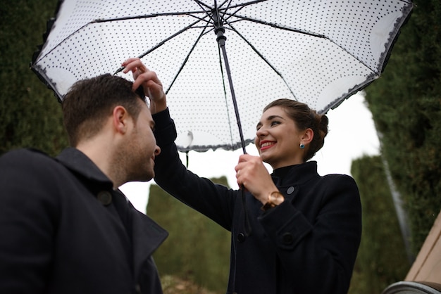Jeune beau couple hispanique aimant se promène sous un parapluie sous la pluie sur la Plaza Espagne. Couple posant dans le contexte du Musée National d'Art de Catalogne.