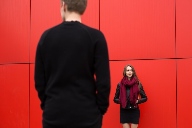 Jeune beau couple posant sur un mur rouge