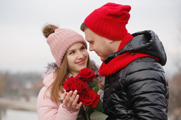 Jeune beau couple avec des roses rouges à l'extérieur