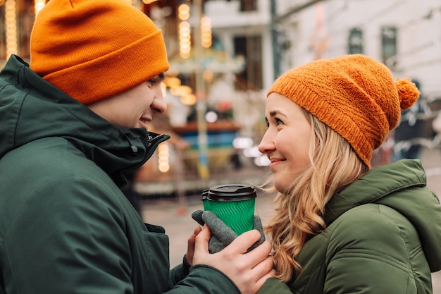 Jeune beau couple s'amusant ensemble à l'extérieur tenant du café et se sentir chaud et heureux