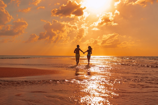 Jeune beau couple se promène le long du bord de mer au coucher du soleil. Voyage de noces. Voyage romantique.