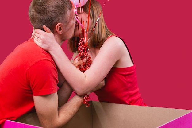 Jeune beau couple en t-shirts rouges s'embrassent sur fond rouge dame blonde a accepté le mariage...