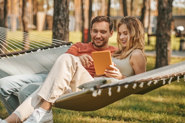 Jeune beau couple avec tablette sur hamac