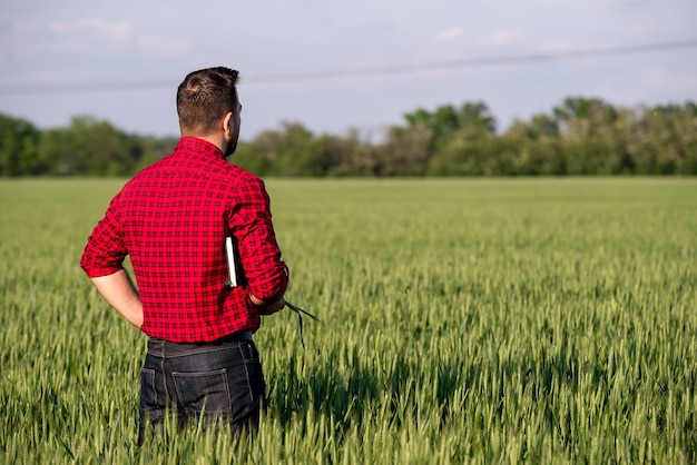 Jeune beau fermier avec journal debout dans un champ de blé