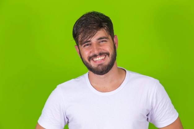 Jeune beau garçon souriant à la caméra isolé sur fond vert Jeune garçon avec un sourire confiant regardant la caméra