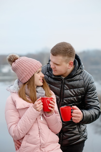 Jeune, beau et heureux couple lors d'un pique-nique, ils boivent du thé chaud