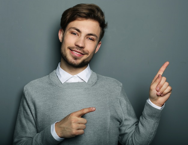 Jeune et beau homme d'affaires pointant vers le haut avec ses doigts