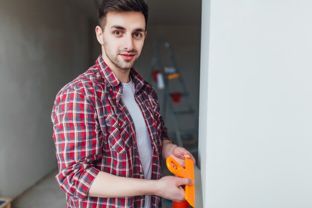 Jeune beau mâle avec une spatule sur les mains, faisant des réparations