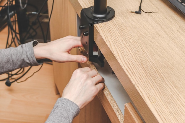 Un jeune beau mec caucasien fixe un support noir à l'arrière d'un bureau en bois