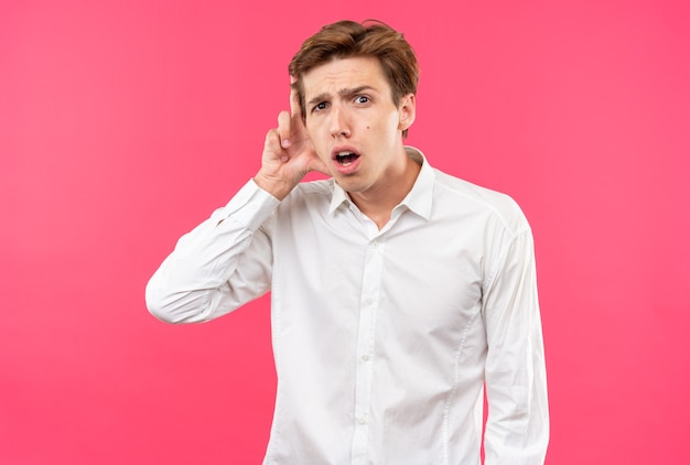 Jeune beau mec concerné portant une chemise blanche mettant la main sur l'oreille