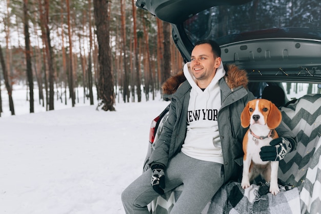 Jeune Beau Mec Dans Une Forêt D'hiver Enneigé Est Assis Dans Le Coffre De Sa Voiture