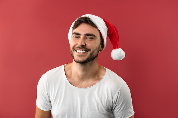 Jeune beau mec dans un t-shirt blanc et un bonnet de Noel