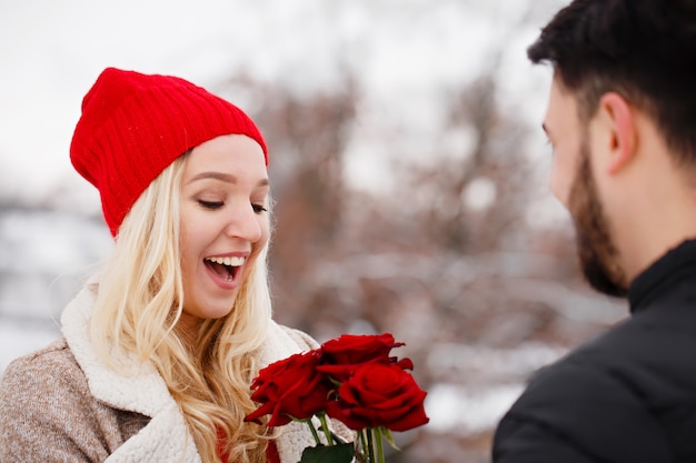 Jeune beau mec donnant à une fille un bouquet de roses le jour de la Saint-Valentin