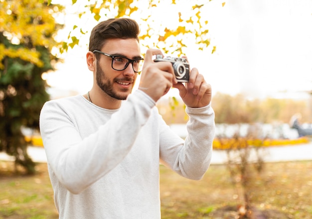 Jeune beau mec hipster se promène dans un magnifique parc d&#39;automne