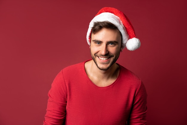 Jeune beau mec en pull rouge et bonnet de Noel