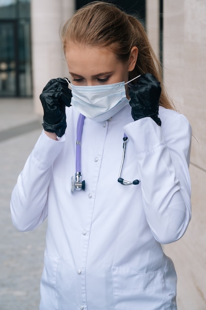 Jeune beau médecin avec un masque de protection et des gants