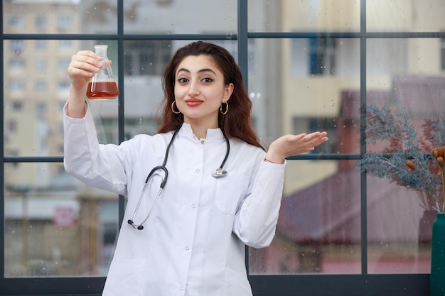 Jeune beau médecin tenant une bouteille de produits chimiques et ouvre sa main Photo de haute qualité