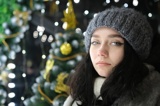 Jeune beau visage heureux de fille souriante posant Noël sur fond Bonne année avec des lumières