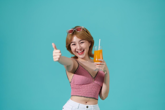 Jeune beauté en été Femme avec des lunettes de soleil boit du jus d'orange en été montrant le pouce vers le haut