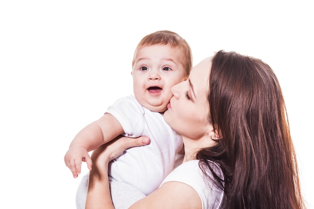 Jeune beauté mère embrassant son bébé sur fond blanc