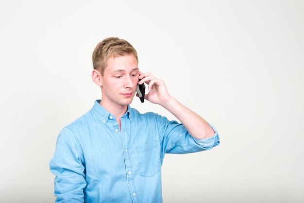 jeune bel homme d'affaires aux cheveux blonds contre un mur blanc