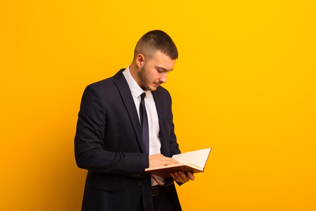 Jeune bel homme d'affaires contre un mur plat avec un livre de journal