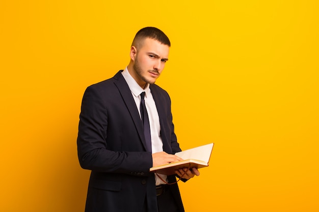 Jeune bel homme d'affaires contre un mur plat avec un livre de journal