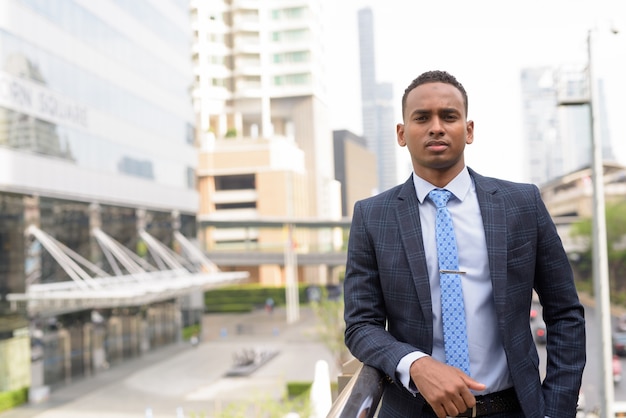 Jeune bel homme d'affaires en costume contre vue du bâtiment moderne à l'extérieur