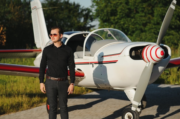 Jeune bel homme d'affaires debout près d'un avion privé