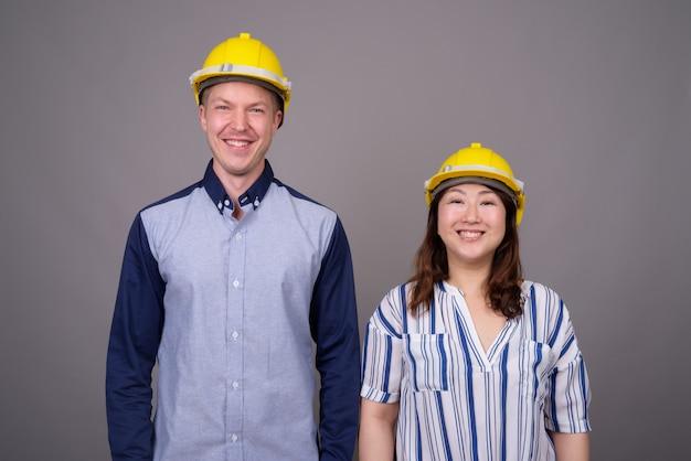 jeune bel homme d'affaires et femme d'affaires asiatique mature portant un casque