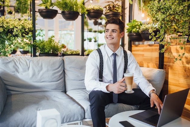 Jeune bel homme d'affaires portant une chemise blanche et une cravate, ordinateur portable de travail