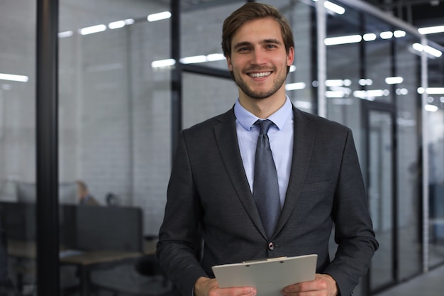 Jeune bel homme d'affaires souriant dans un environnement de bureau