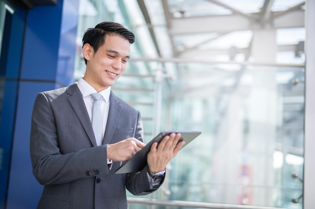 Jeune bel homme d'affaires tenant une tablette à la recherche de suite.