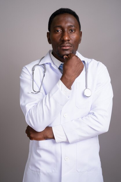 Jeune bel homme africain médecin sur fond gris